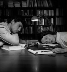 an old photo of two people laying on the floor with books in front of them