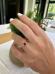 a woman's hand with a ring on it and a plant in the background