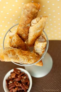 some food is in a glass on a table next to a bowl with nuts and pecans