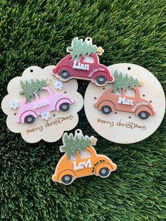 three wooden christmas ornament with cars and trees on them, sitting in the grass