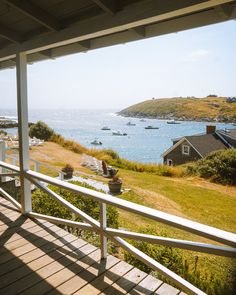 a view of the ocean and boats from a porch in front of a house with white railings