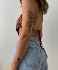 the back of a woman's body with tattoos on her left arm and shoulder