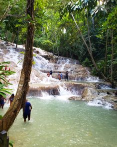 people are standing in the water near a waterfall