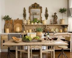 a wooden table topped with lots of food next to a wall mounted shelf filled with pots and pans