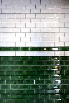 a green and white tiled wall in a bathroom