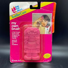 a pink plastic toy in the packaging for children's hairbrushes and combs