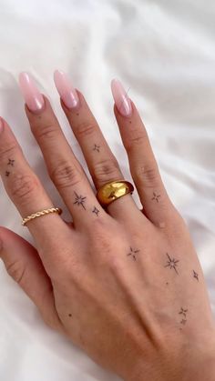 a woman's hand with pink nails and gold ring on her left thumb, showing stars