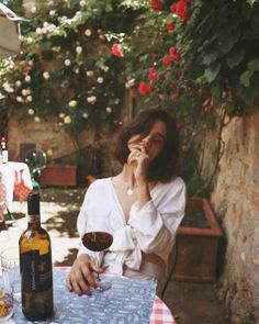 a woman sitting at a table with a glass of wine