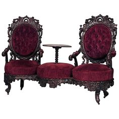 two chairs and a table are shown with red velvet upholstered cushions on them