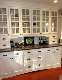 a kitchen with white cabinets and black counter tops