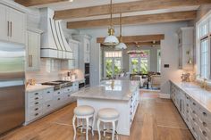 a large kitchen with white cabinets and counter tops, along with an island in the middle