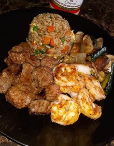 a black plate topped with meat and veggies next to a bottle of beer