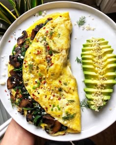 an omelet on a white plate with sliced avocado