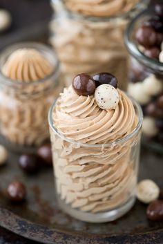 three small jars filled with desserts on top of a metal tray next to chocolate candies