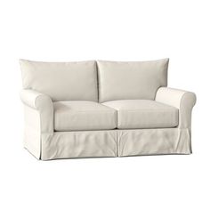 a white couch with two pillows on the back and one arm folded over it's head