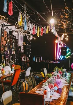 a long table is set up for a party with colorful lights hanging from the ceiling