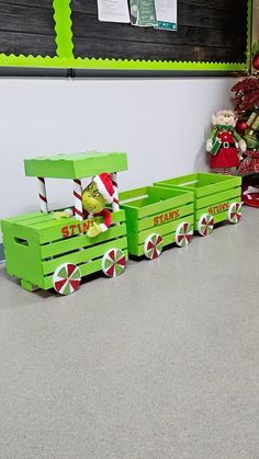 a green toy train with candy canes on the front and sides, sitting next to a christmas tree