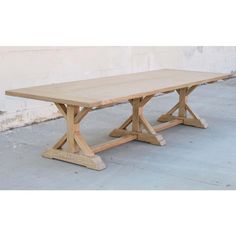 a wooden table sitting on top of a cement floor next to a white brick wall