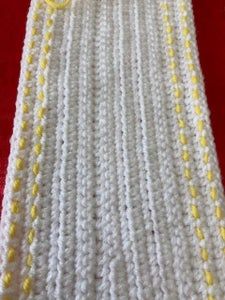 a crocheted white and yellow blanket on a red surface