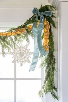 a green ribbon hanging from the side of a window with pine cones and oranges on it