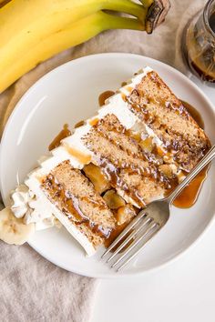 a piece of cake on a white plate with bananas and caramel drizzle