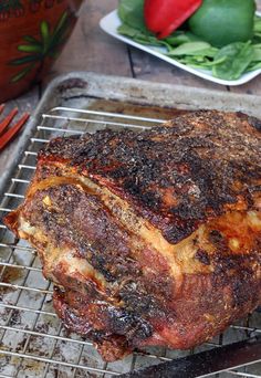 a large piece of meat sitting on top of a metal rack next to some vegetables