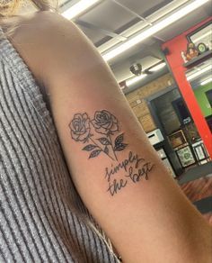 a woman with a tattoo on her arm that says simply the best and three roses