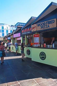 people are standing outside of a wood fired pizza stand