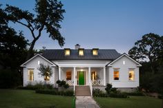 a white house lit up at night with green door and steps leading to the front