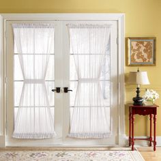 an open white door with sheer curtains on the inside and outside, in front of a yellow wall