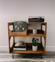 a wooden shelf with books and magazines on it next to a plant in a pot