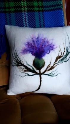 a white pillow with a purple flower on it