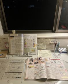 an open book sitting on top of a white desk next to a computer keyboard and monitor