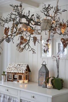 a white table topped with lots of ornaments and lights hanging from the ceiling above it