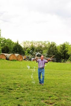 a man standing on top of a lush green field next to a wooden barrel filled with water