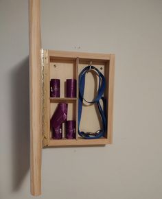 a wooden box with purple items in it and a pair of scissors hanging on the wall