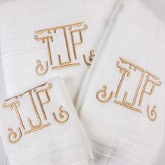 three white towels with gold embroidered monogrammed letters and the word tf on them