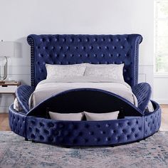 a large blue bed sitting on top of a wooden floor