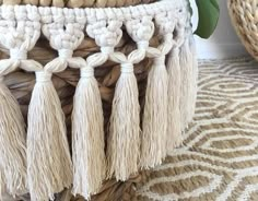 a woven basket with tassels on top of it sitting on a rug next to other baskets