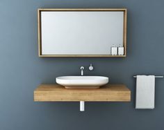 a bathroom sink sitting under a mirror on top of a wooden counter next to a towel rack