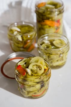 pickled onions and peppers in jars on a table