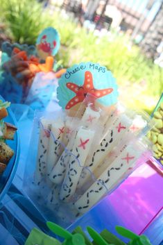 there are many snacks on the table with blue plates and cups next to each other