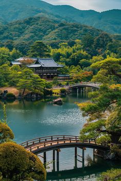 a bridge over a body of water surrounded by trees and bushes in front of a mountain range