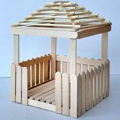 a wooden toy house made out of popsicle sticks and some sort of slatted roof