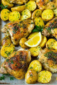 chicken, potatoes and lemons on a baking sheet with parsley sprinkled on top