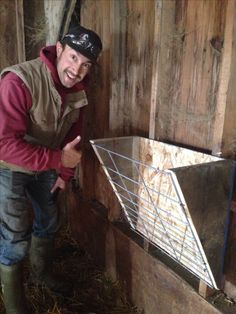 a man standing next to a metal trough filled with hay and looking at the camera