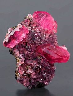 a cluster of pink crystals sitting on top of a black table next to a gray wall