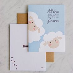 two greeting cards with sheep on them sitting next to each other in front of a marble background