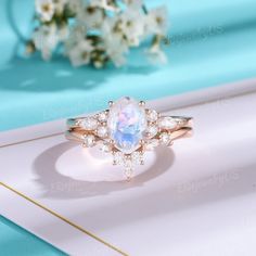 a ring with an oval shaped rainbow colored stone surrounded by small white diamonds