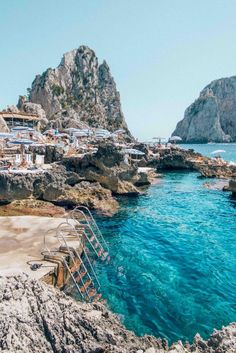 the beach is surrounded by rocks and blue water